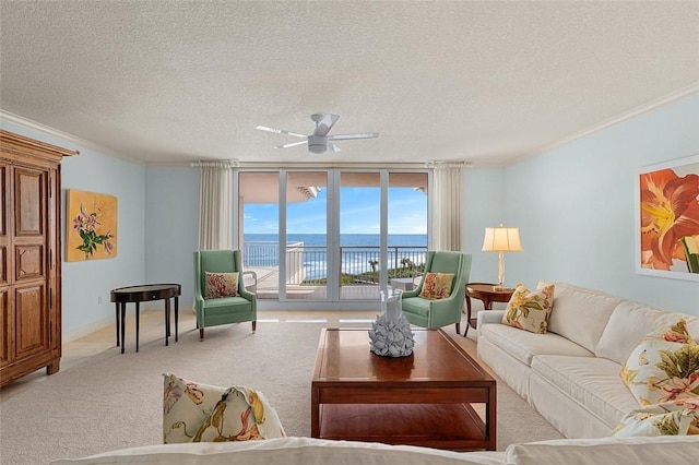 carpeted living room with ornamental molding, ceiling fan, floor to ceiling windows, a water view, and a textured ceiling