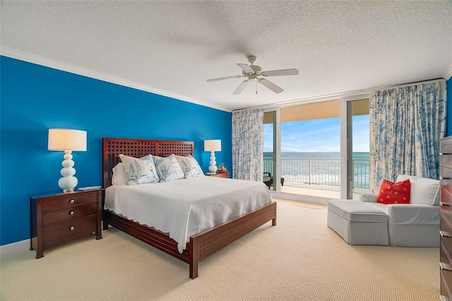 bedroom featuring expansive windows, ornamental molding, a water view, and access to outside