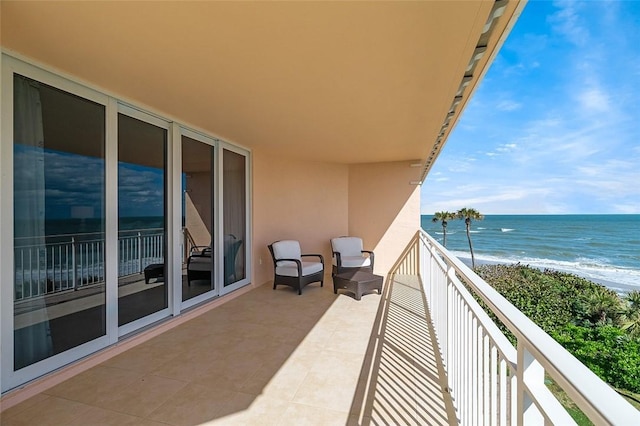 balcony with a water view and a view of the beach