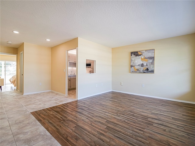 unfurnished room with light wood-type flooring and a textured ceiling