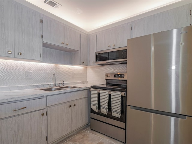 kitchen featuring stainless steel appliances, sink, decorative backsplash, and light brown cabinets