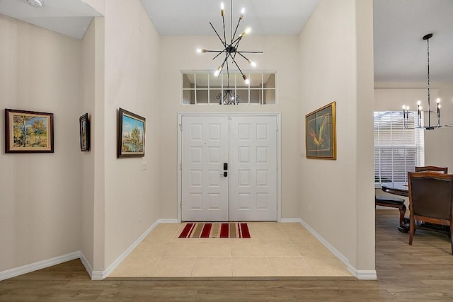 foyer entrance with a high ceiling, a notable chandelier, and light hardwood / wood-style flooring