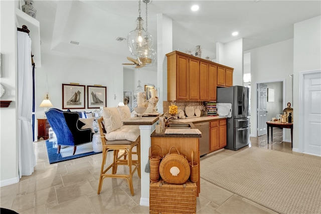 kitchen featuring kitchen peninsula, tasteful backsplash, a breakfast bar, appliances with stainless steel finishes, and decorative light fixtures