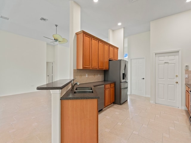 kitchen with kitchen peninsula, decorative backsplash, sink, ceiling fan, and appliances with stainless steel finishes