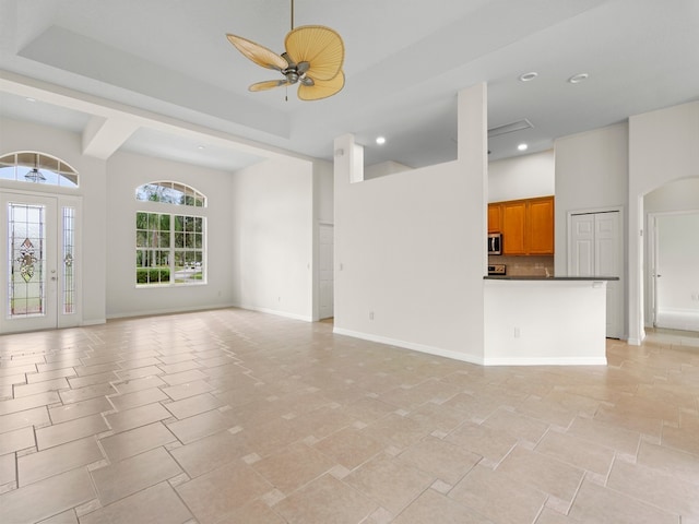 unfurnished living room with ceiling fan and a high ceiling