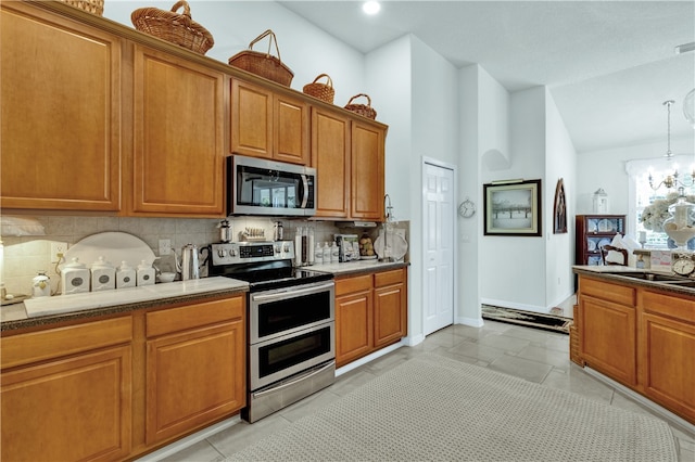 kitchen with an inviting chandelier, decorative backsplash, light tile patterned flooring, appliances with stainless steel finishes, and decorative light fixtures