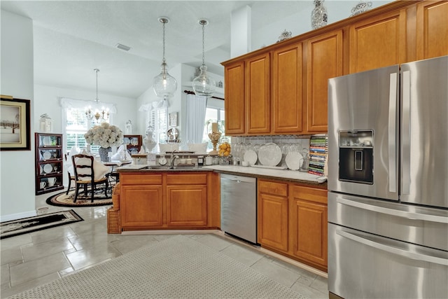 kitchen featuring stainless steel appliances, plenty of natural light, decorative light fixtures, and vaulted ceiling