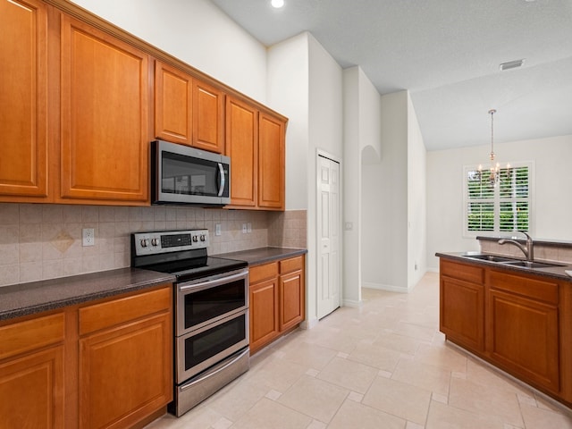 kitchen with tasteful backsplash, appliances with stainless steel finishes, pendant lighting, an inviting chandelier, and sink