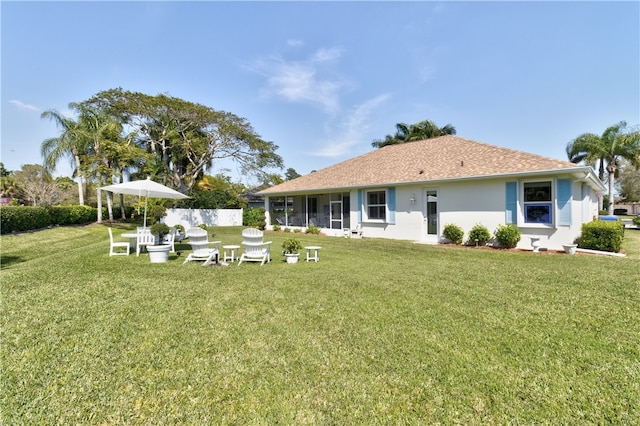 rear view of house with a sunroom and a yard