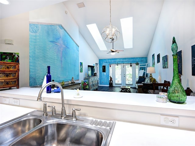 kitchen with ceiling fan with notable chandelier, sink, decorative light fixtures, and vaulted ceiling with skylight