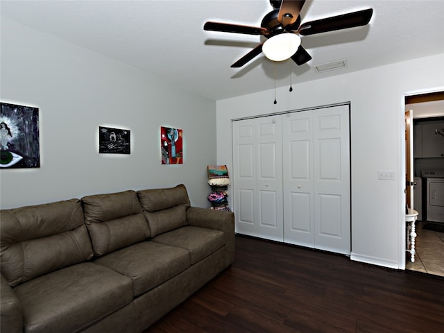 living room with dark wood-type flooring, washer and dryer, and ceiling fan