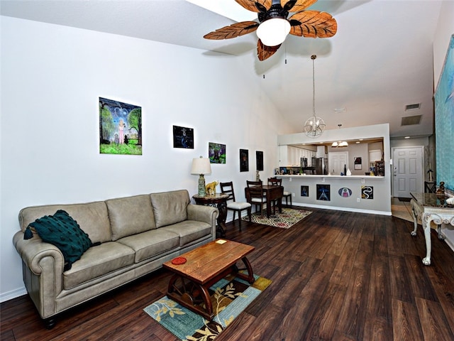 living room with ceiling fan with notable chandelier, hardwood / wood-style flooring, and high vaulted ceiling