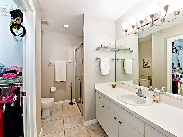 bathroom with toilet, vanity, tile patterned floors, and a shower with shower door