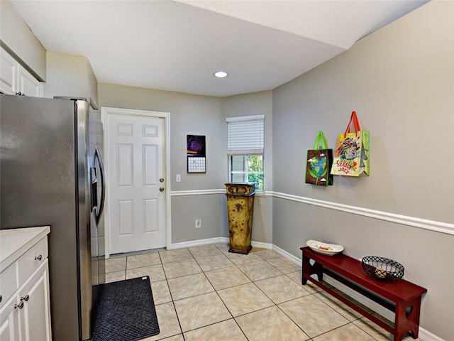 kitchen featuring white cabinets, stainless steel fridge with ice dispenser, and light tile patterned floors