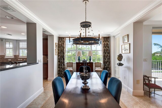 tiled dining room with ornamental molding, a notable chandelier, and a healthy amount of sunlight