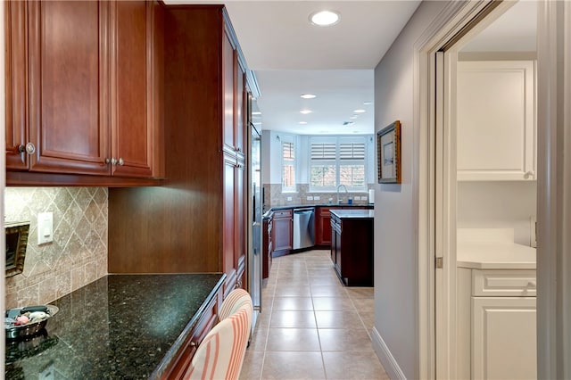 kitchen with decorative backsplash, sink, light tile patterned floors, stainless steel dishwasher, and dark stone countertops