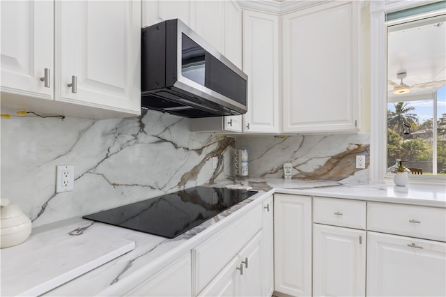 kitchen featuring black electric stovetop, white cabinets, and backsplash