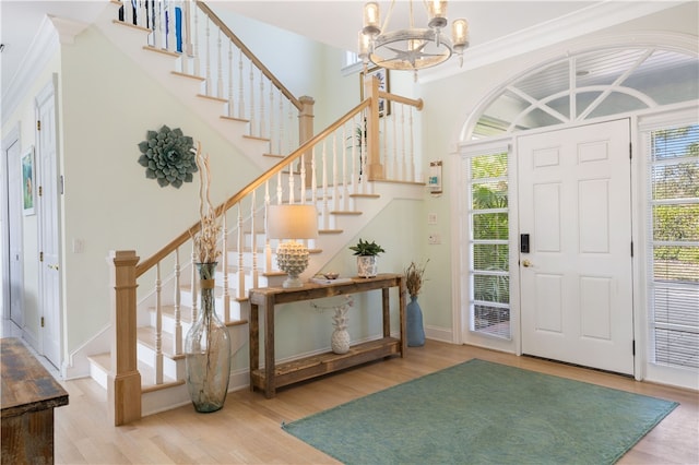 foyer with wood-type flooring, an inviting chandelier, and ornamental molding