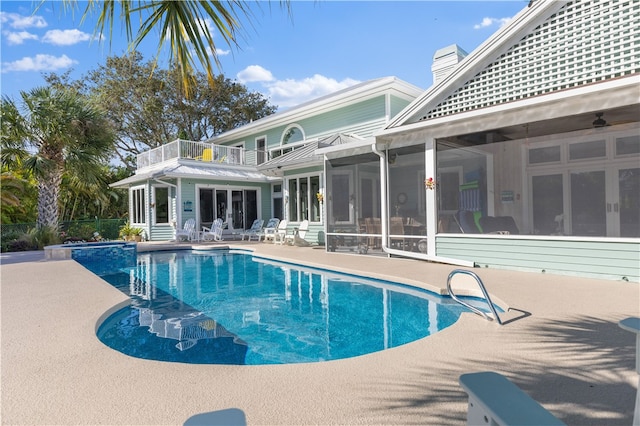 view of swimming pool featuring a patio, a sunroom, and french doors