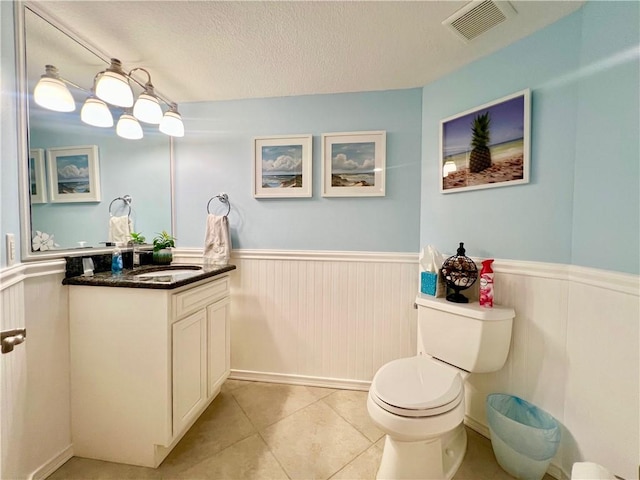 bathroom with tile patterned floors, vanity, toilet, and a textured ceiling