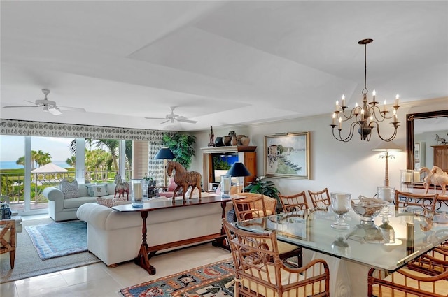 tiled dining space with crown molding, a tray ceiling, and ceiling fan with notable chandelier