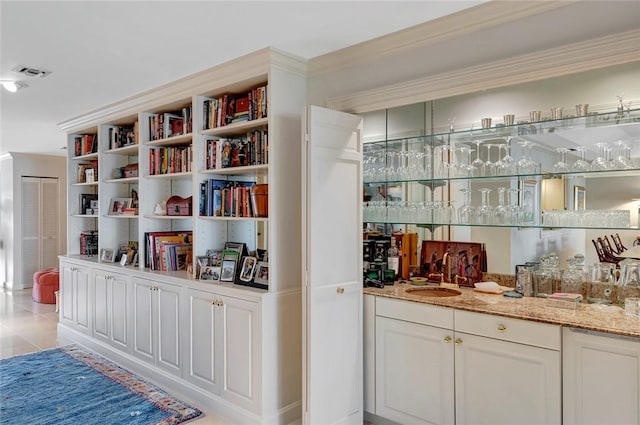 bar with white cabinetry, light stone countertops, and sink