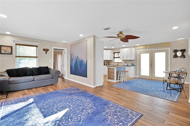 living room with light hardwood / wood-style flooring, french doors, and ceiling fan