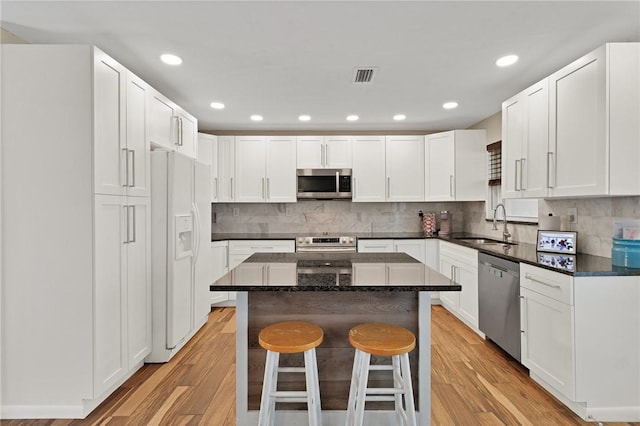 kitchen with stainless steel appliances, a kitchen breakfast bar, white cabinets, and a center island