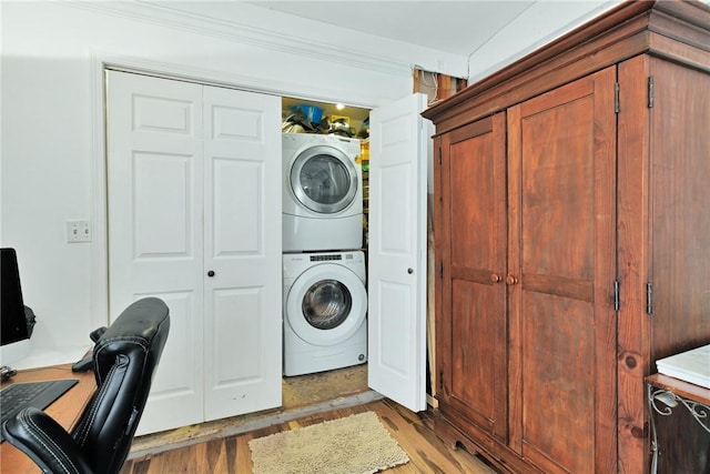 clothes washing area with stacked washing maching and dryer and wood-type flooring