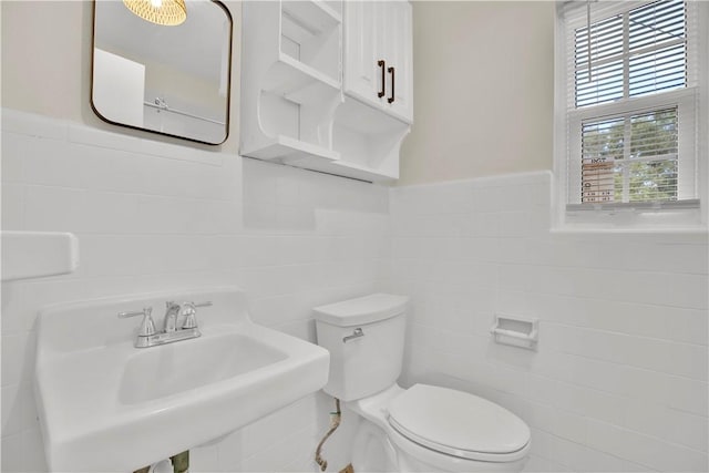 bathroom featuring tile walls, sink, plenty of natural light, and toilet