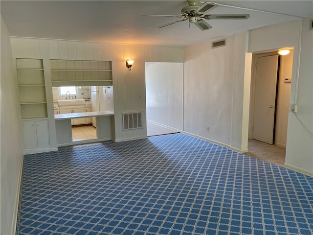 carpeted empty room featuring ceiling fan and sink