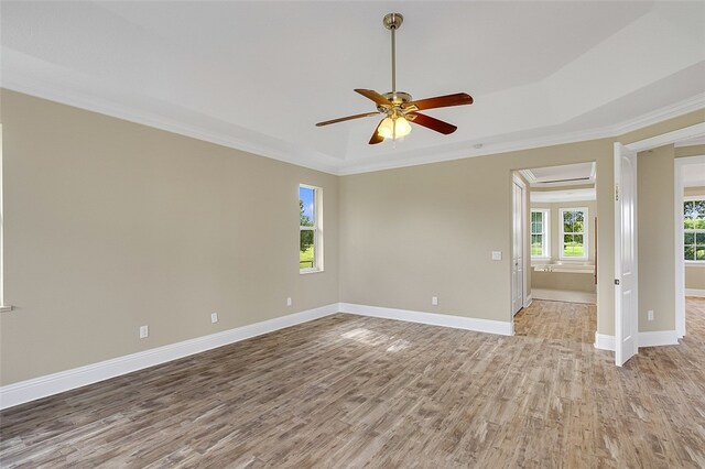 unfurnished room with ceiling fan, ornamental molding, a raised ceiling, and light wood-type flooring