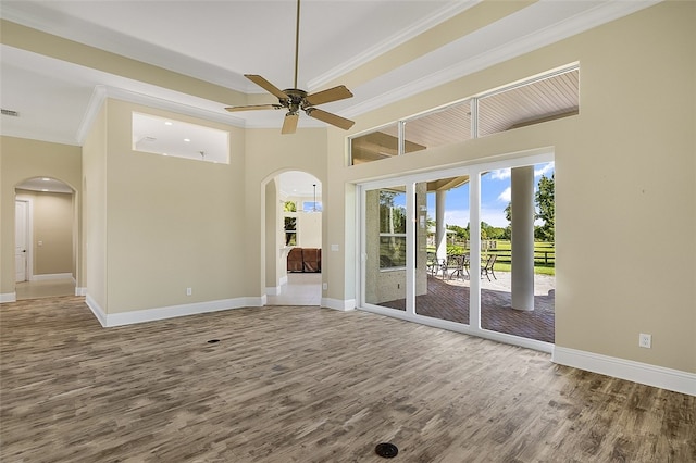 empty room with hardwood / wood-style flooring, ornamental molding, ceiling fan, and a towering ceiling