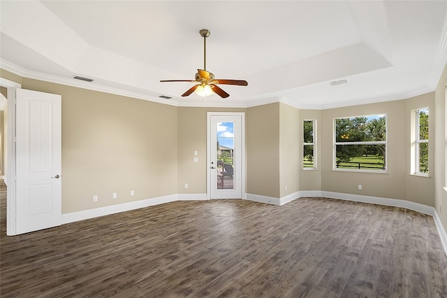 unfurnished room with a raised ceiling, crown molding, dark hardwood / wood-style floors, and ceiling fan