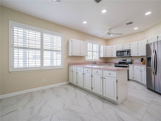 kitchen with white cabinets, plenty of natural light, ceiling fan, and appliances with stainless steel finishes