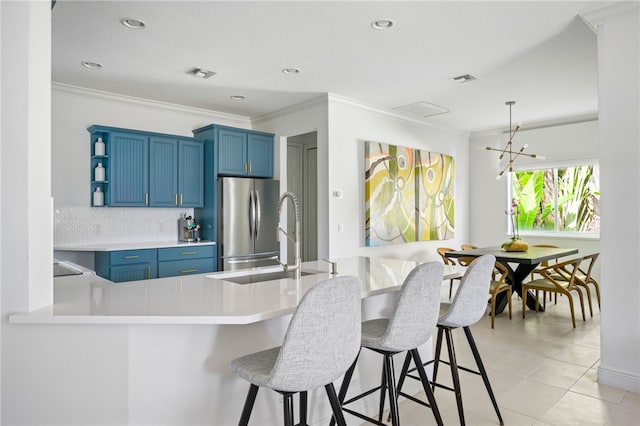 kitchen featuring stainless steel fridge, blue cabinetry, tasteful backsplash, ornamental molding, and kitchen peninsula