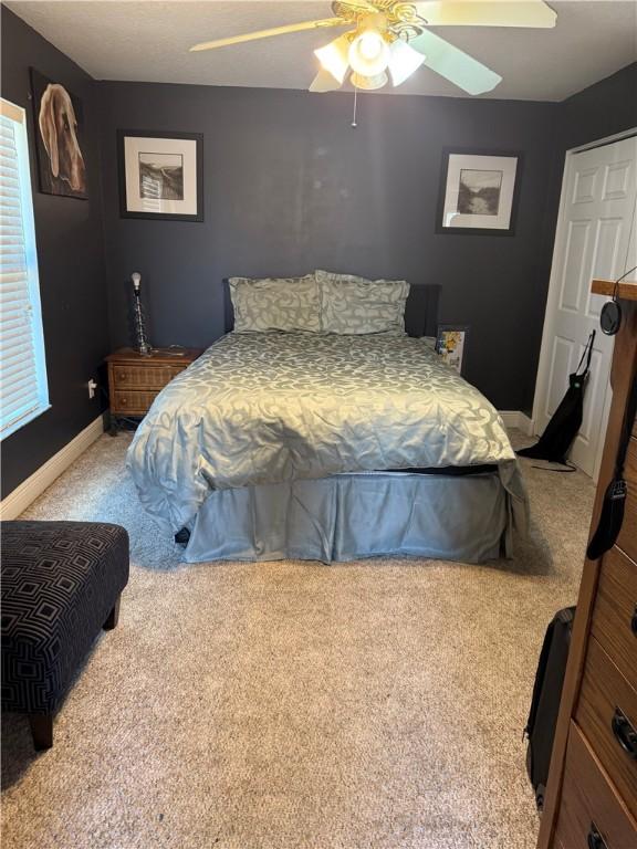 carpeted bedroom with baseboards and a ceiling fan