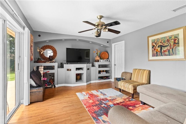 living room with a ceiling fan, visible vents, wood finished floors, and a fireplace