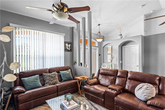 living area featuring vaulted ceiling, a ceiling fan, and a textured ceiling