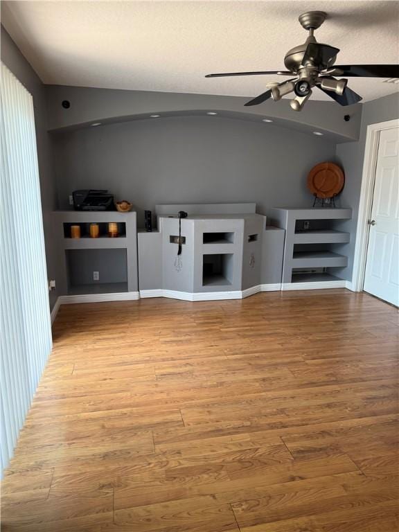 unfurnished living room featuring light wood-type flooring, baseboards, and a ceiling fan