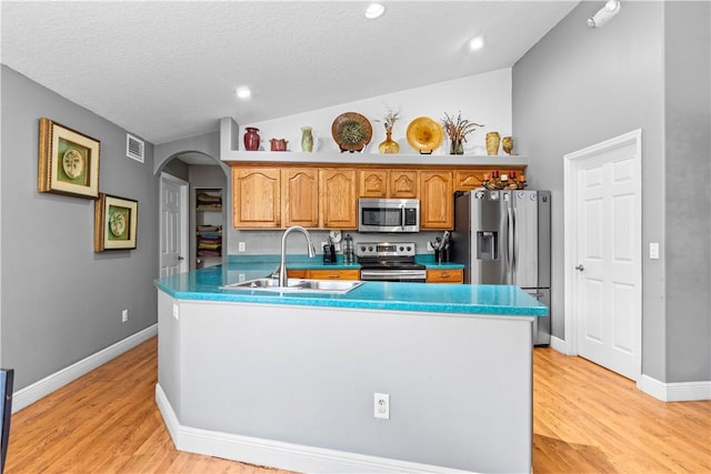kitchen with appliances with stainless steel finishes, a sink, visible vents, arched walkways, and vaulted ceiling