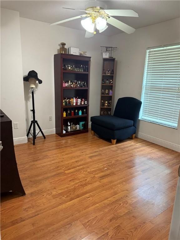 sitting room with baseboards, light wood finished floors, and ceiling fan