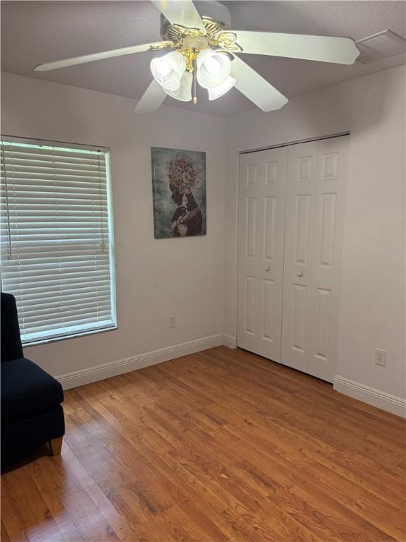 unfurnished bedroom with baseboards, light wood-style floors, a closet, and ceiling fan
