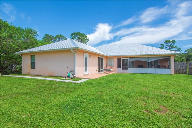 back of house with a lawn, stucco siding, a sunroom, and metal roof