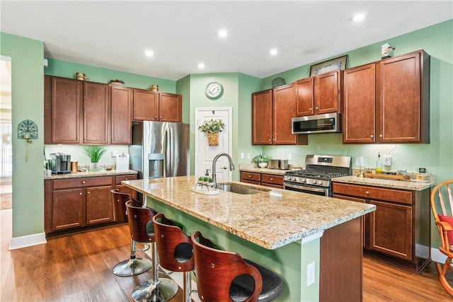 kitchen featuring appliances with stainless steel finishes, sink, dark wood-type flooring, and an island with sink