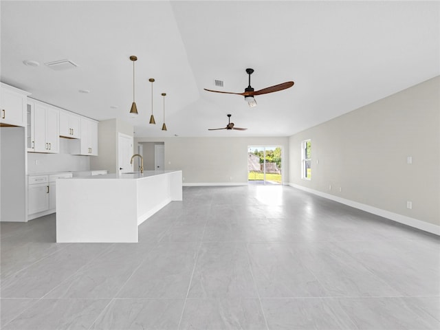 kitchen featuring white cabinets, sink, hanging light fixtures, and a kitchen island with sink