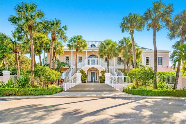 view of front facade with stairs, stucco siding, french doors, covered porch, and driveway