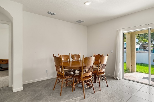 dining area featuring light tile patterned floors and a textured ceiling