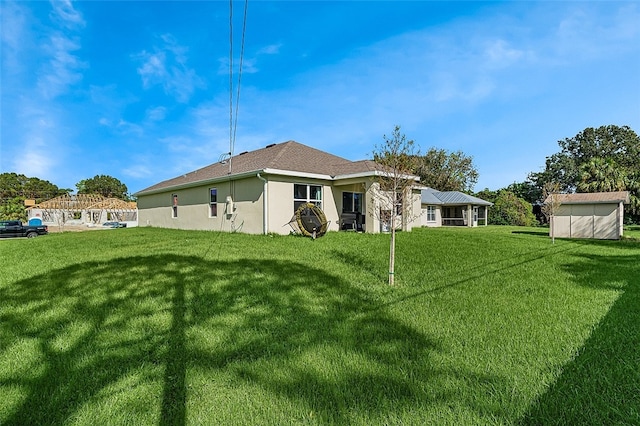 rear view of property with a lawn and a storage unit