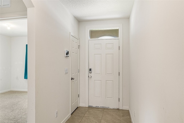 doorway with light carpet and a textured ceiling